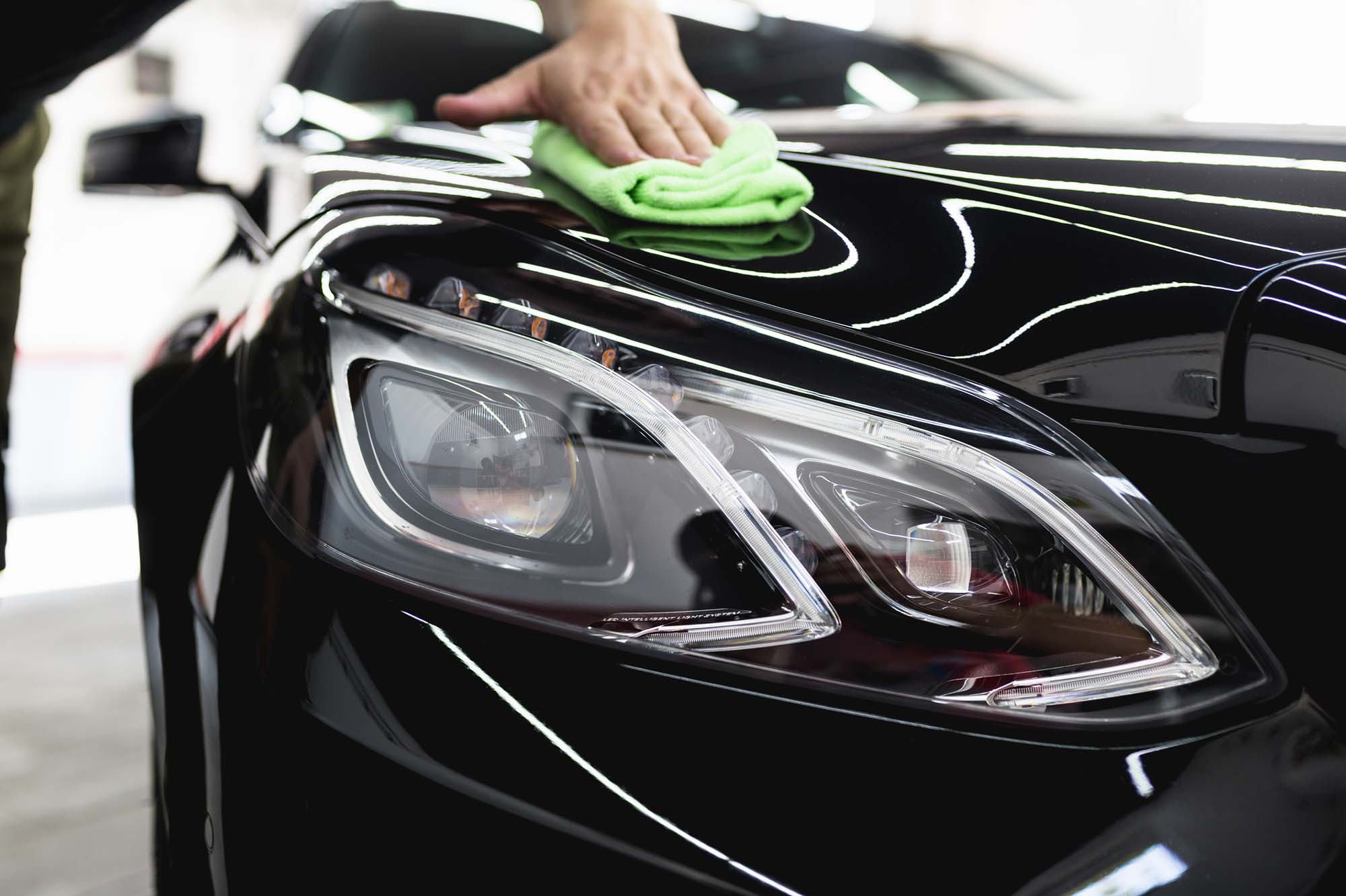 A man cleaning car with microfiber cloth, car detailing or valeting concept.