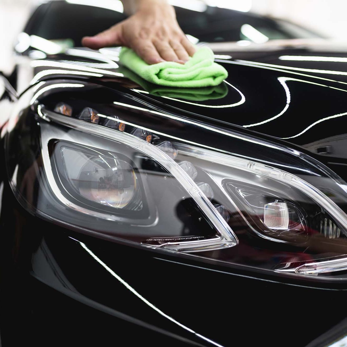 A man cleaning car with microfiber cloth, car detailing or valeting concept.